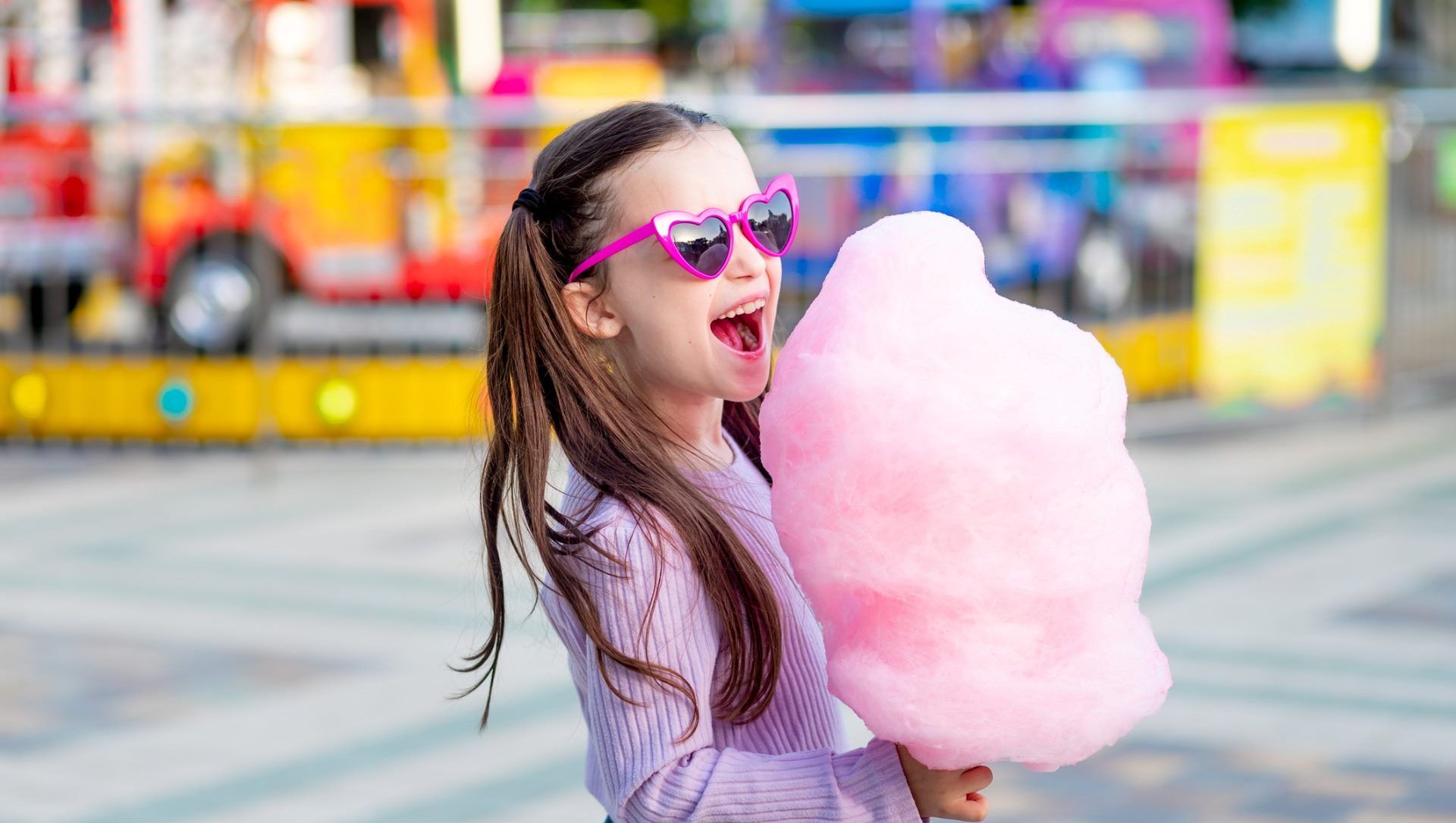 Child girl in an amusement park in the summer eating fairy floss - Cashrewards.jpg