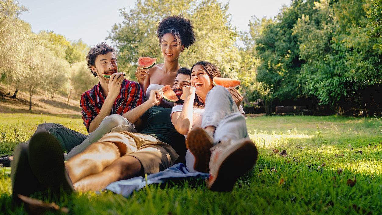 friends eating watermelon on the grass in a park